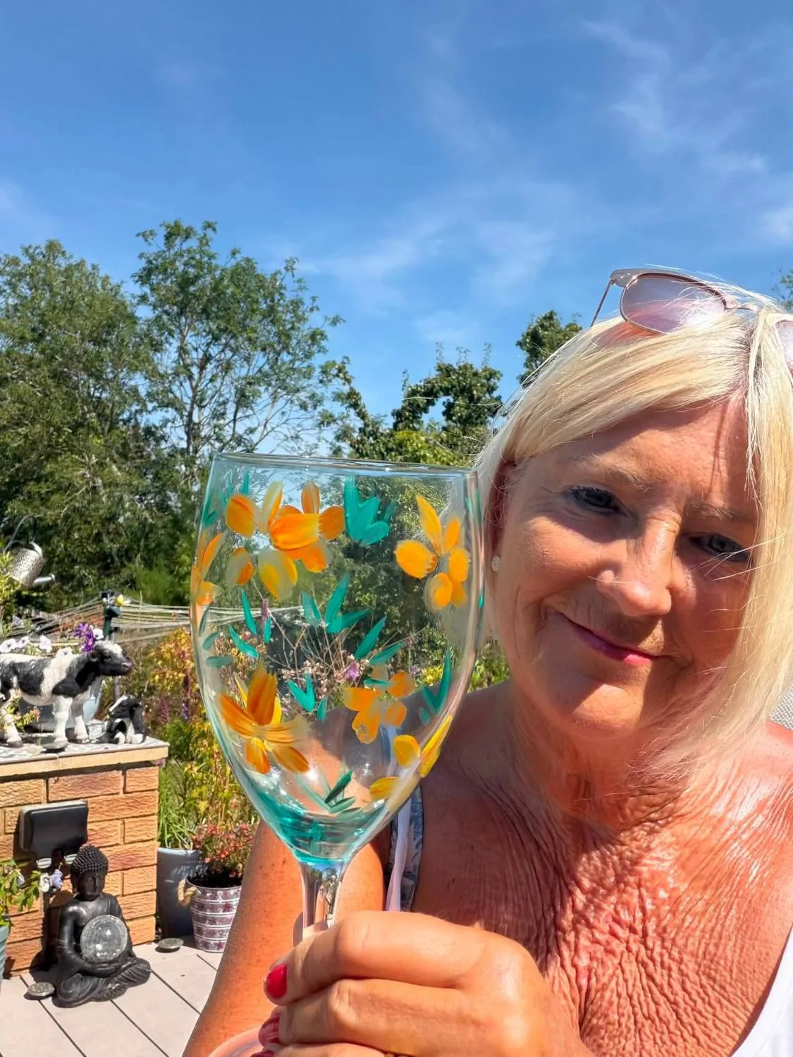 Sally holding a wine glass painted with orange daffodils